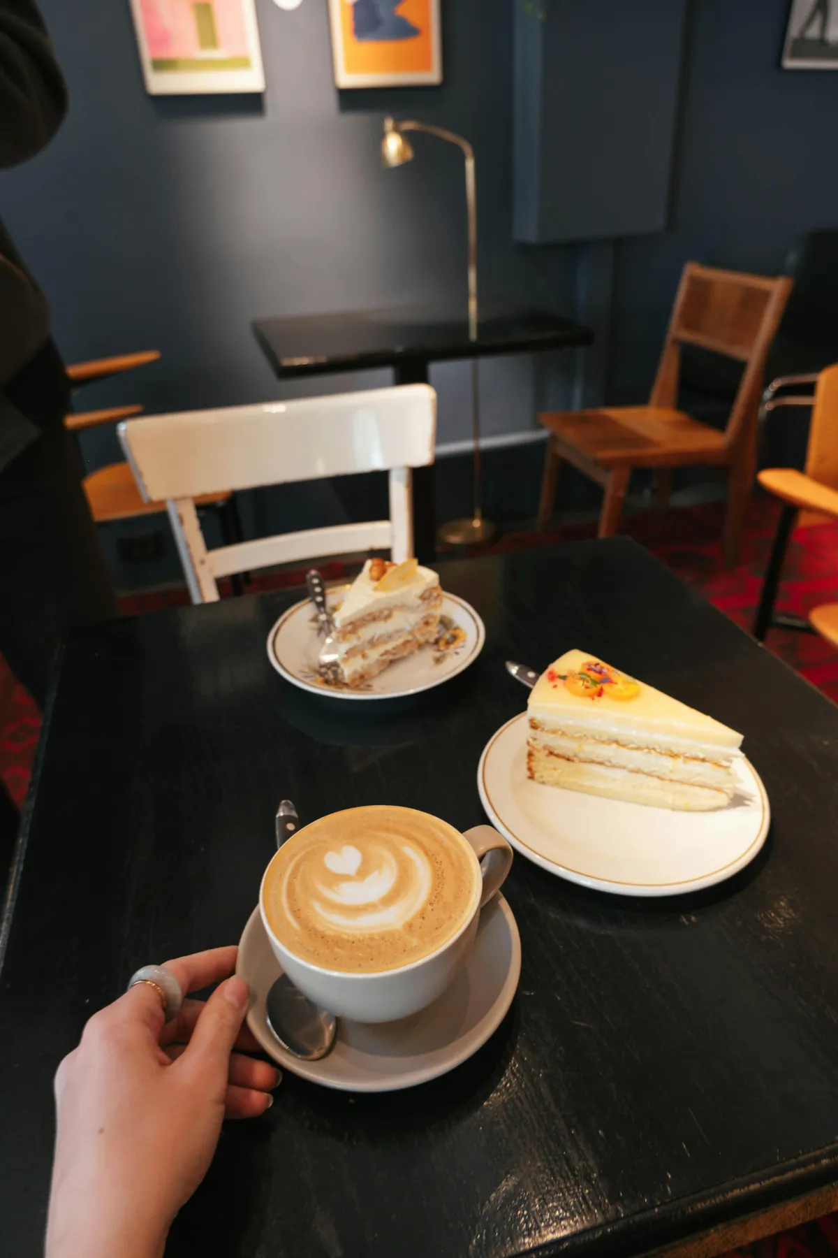 Flat White und zwei Stücke Kuchen auf einem dunklen Tisch